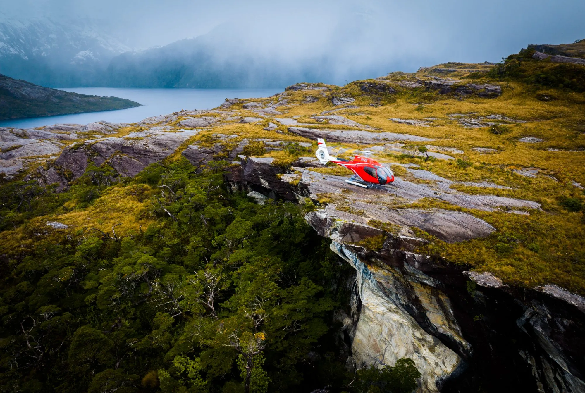 Wolo helicopter landed on a remote clifftop above a Patagonian fjord